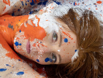 Rothaarige - im Gesicht und am Oberkörper mit Farbklecksen bespritzt.