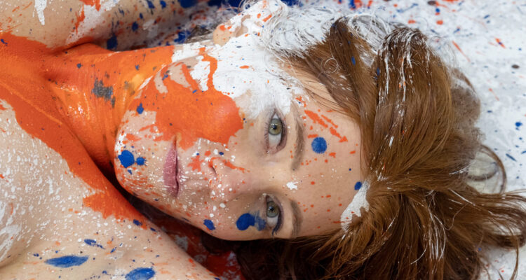 Rothaarige - im Gesicht und am Oberkörper mit Farbklecksen bespritzt.