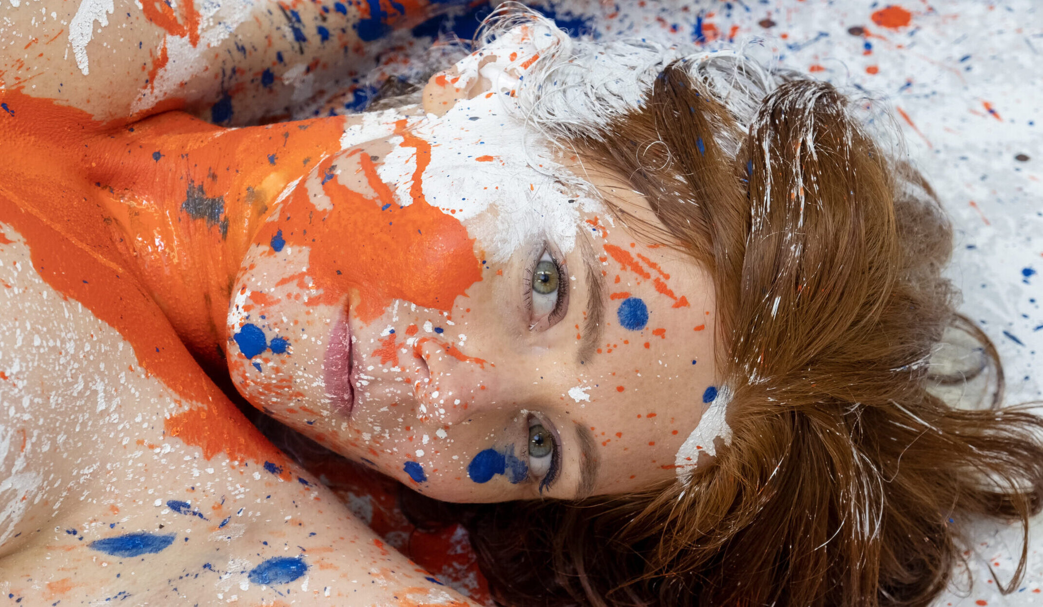 Rothaarige - im Gesicht und am Oberkörper mit Farbklecksen bespritzt.